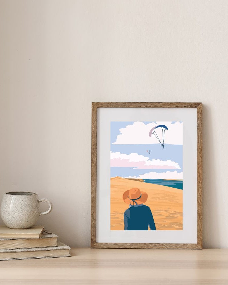 Affiche de la Dune du Pilat dans un cadre en bois, présentée dans un environnement minimaliste.