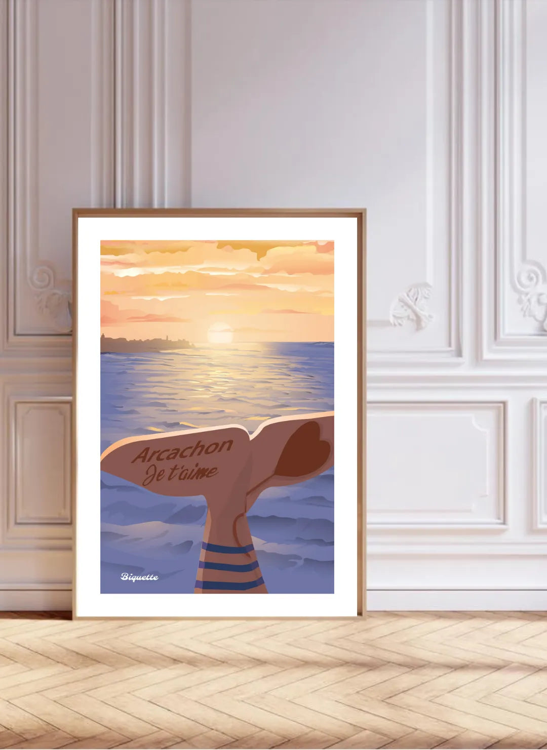 Grand poster encadré bois posé au sol contre un mur blanc à moulures classiques et parquet en chevrons, alliant design moderne et architecture traditionnelle.