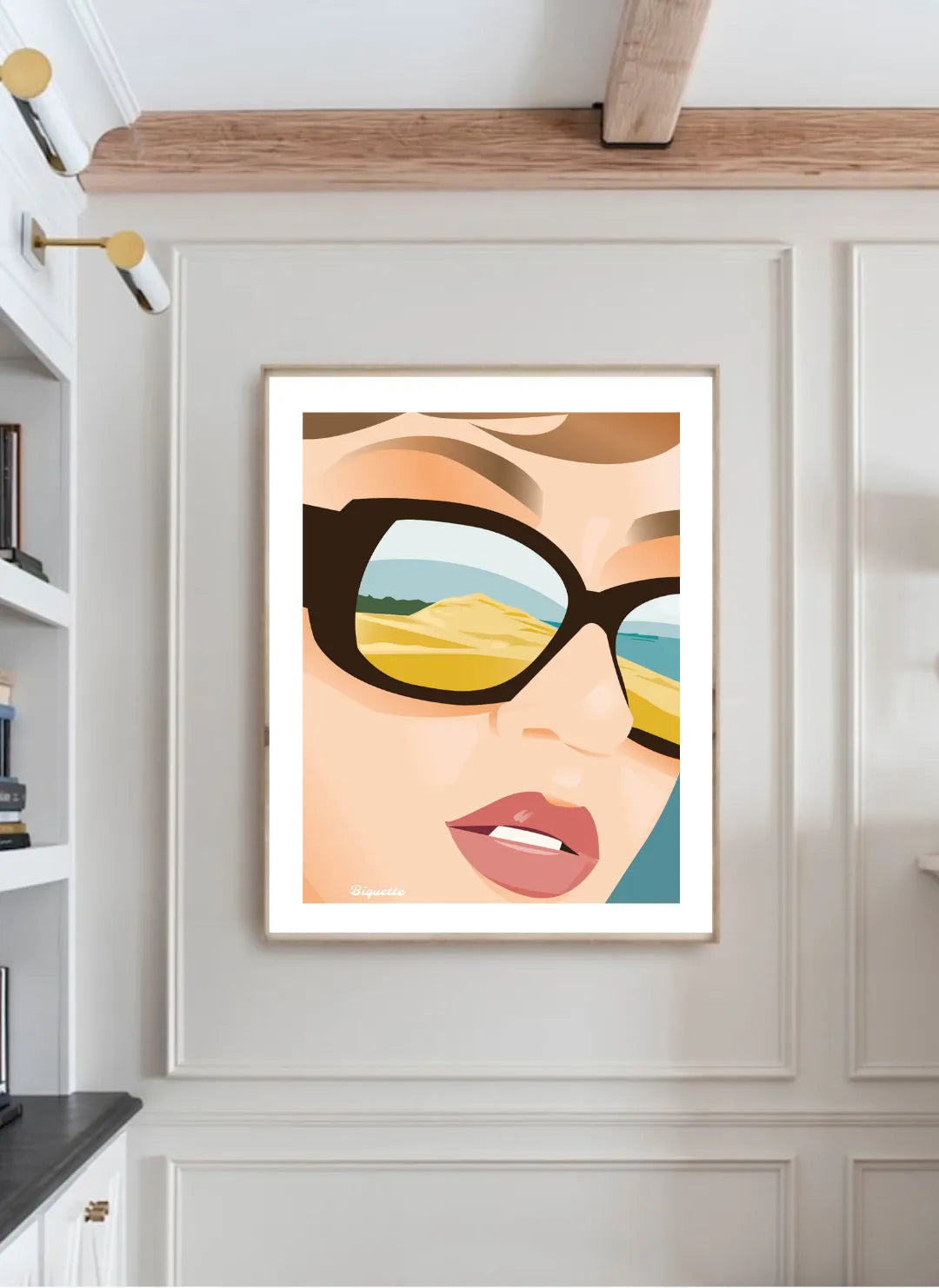 Affiche de la Dune du Pilat avec cadre noir minimaliste posée sur un buffet en bois sombre, entourée de poteries artisanales dans une ambiance intérieure chaleureuse et sobre.