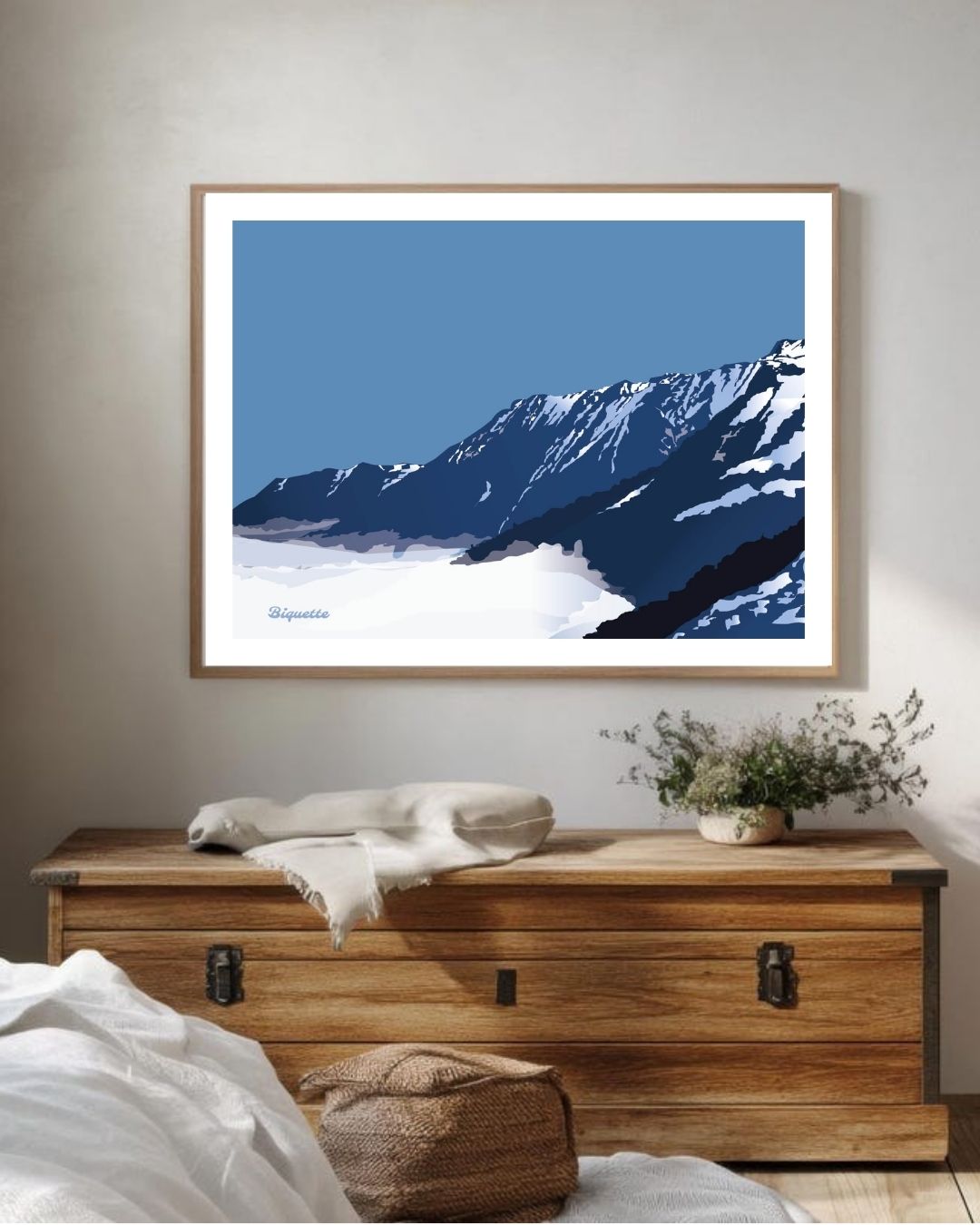 Illustration néo-rétro du sommet enneigé de Piau-Engaly au-dessus d'une mer de nuages, encadrée au-dessus d'une commode en bois brut rustique.