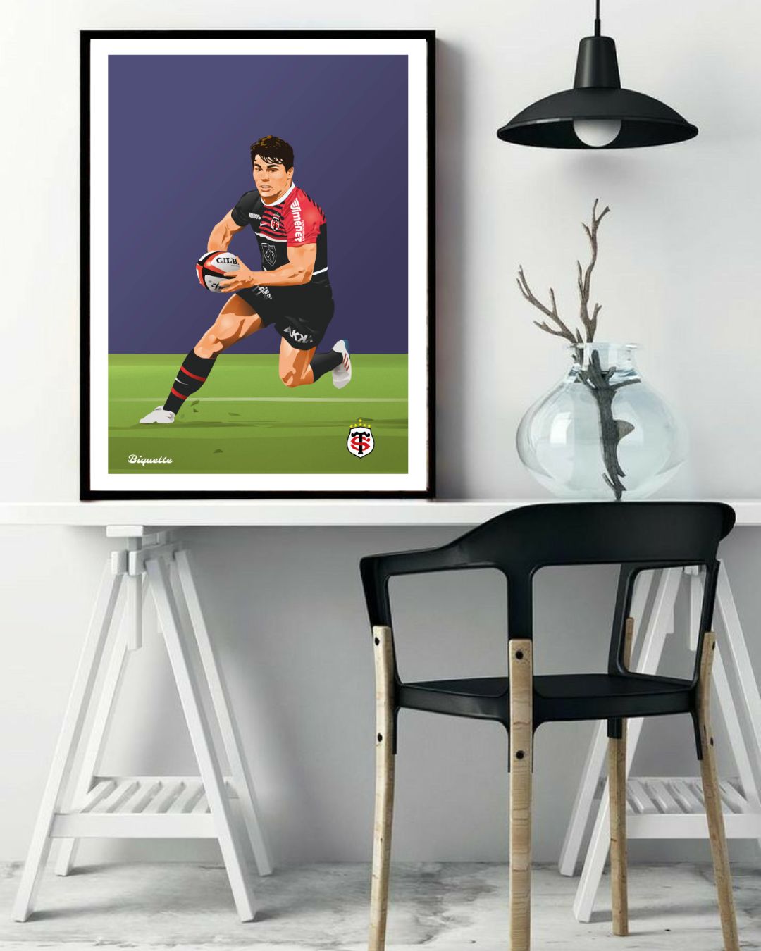 Affiche encadrée d'Antoine Dupont avec le maillot de Toulouse suspendue au-dessus d'un bureau blanc équipé d'une chaise design noire.