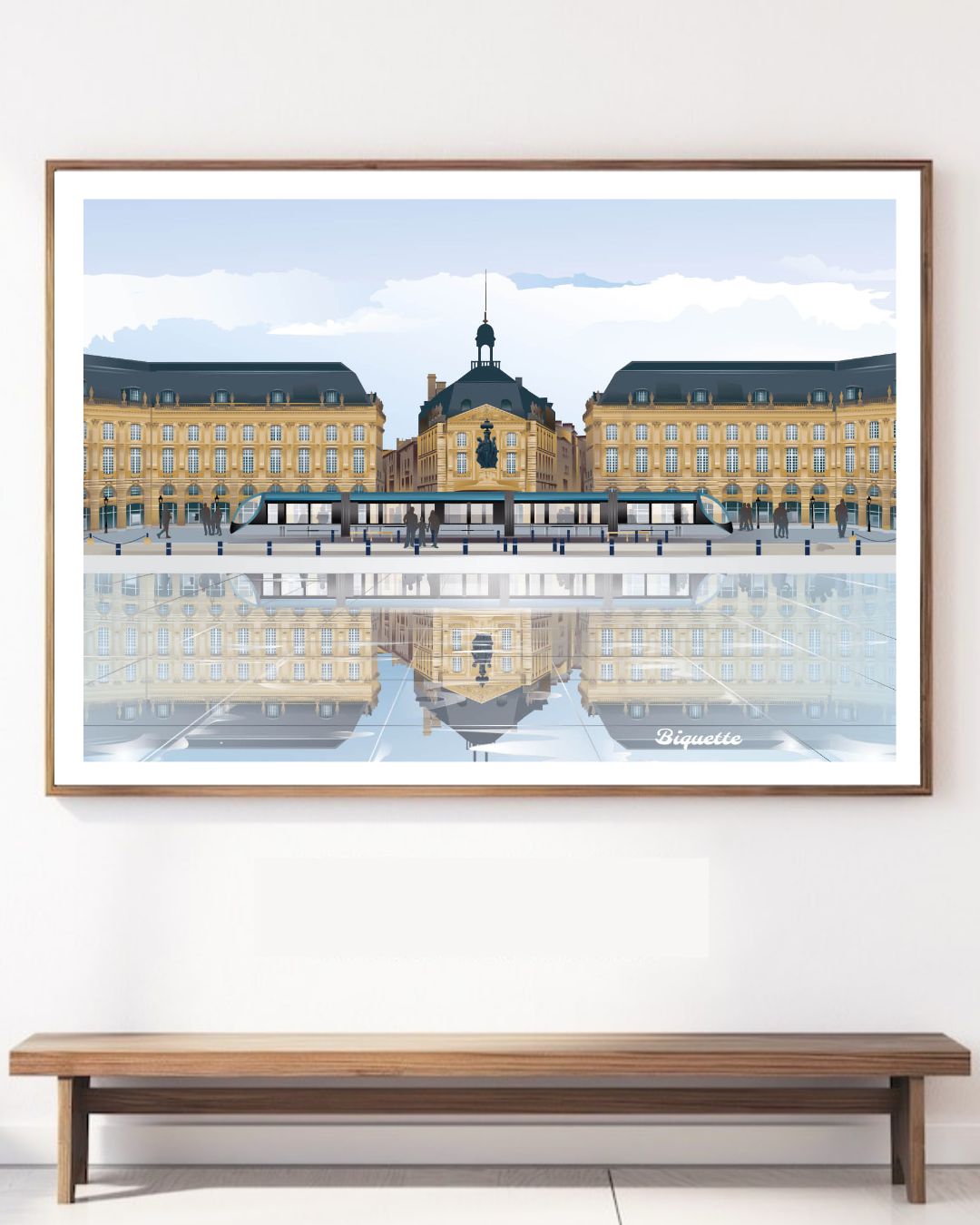 Grand cadre en bois clair affichant l'illustration de la Place de la Bourse et du Miroir d'Eau de Bordeaux, fixé au-dessus d'un banc en bois minimaliste.