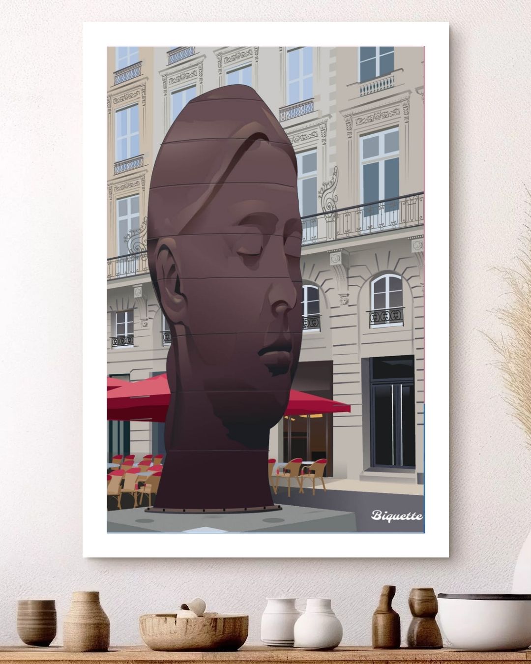 Affiche de la sculpture Sanna de la place de la Comédie à Bordeaux, encadrée et mise en scène au-dessus d'une étagère décorée de poteries artisanales.