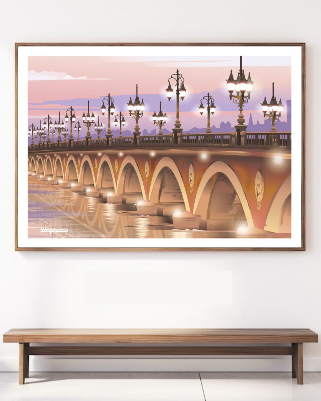 Affiche horizontale du Pont de Pierre éclairé, suspendue au-dessus d'un banc en bois minimaliste contre un mur blanc épuré.