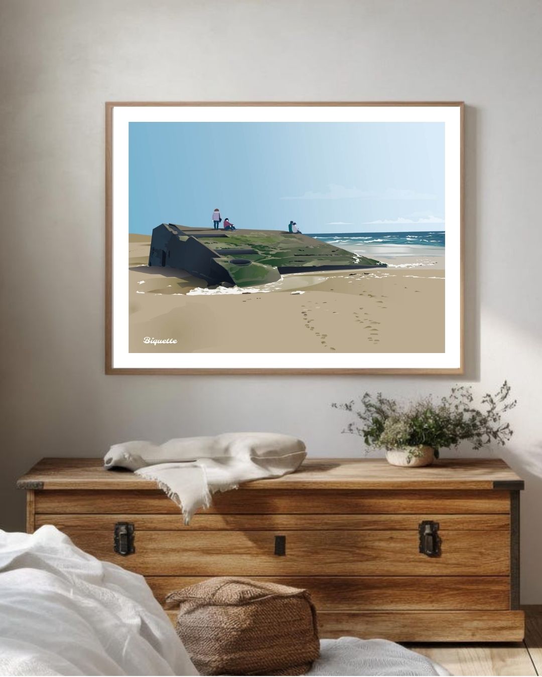Affiche encadrée de la plage et du blockhaus du Cap Ferret par Monsieur Biquette, installée au-dessus d'un meuble en bois rustique.