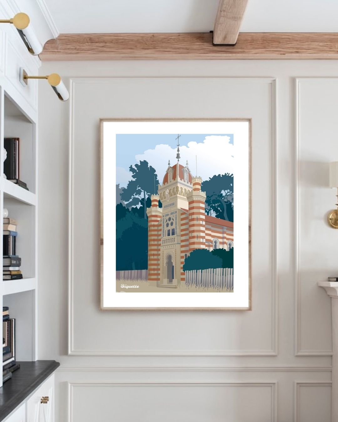 Affiche encadrée de la Chapelle Algérienne de Monsieur Biquette suspendue dans un coin bureau lumineux à côté d'une bibliothèque blanche.